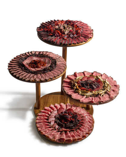 Next Level Taste 4 Tier board of rolled kosher deli meats on a tiered display, white background